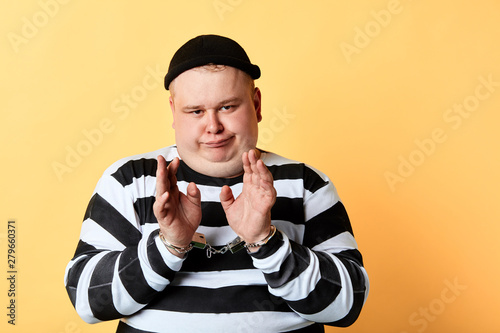 criminal is afraid of policemen, thief has been cought by police. isolated yellow background. studio shot. photo