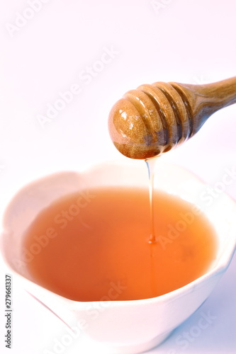 honey on wooden scoop drop to cup in white background