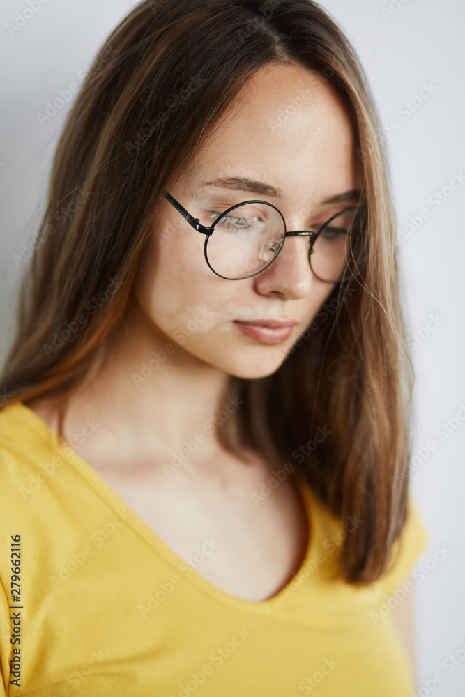sad unhappy depressed girl wearing yellow T-shirt in glasses looking down. sadness, depression . negative emotion