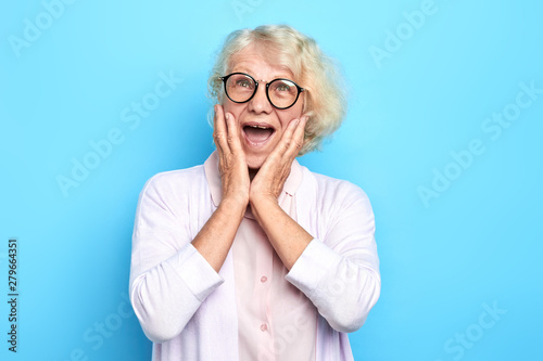 senior emotional doctor woman terrified with fear, shouting in shock. Panic concept.woman in glasses with wide open mouth expresses fear, surprise. isolated blue background. studio shot.