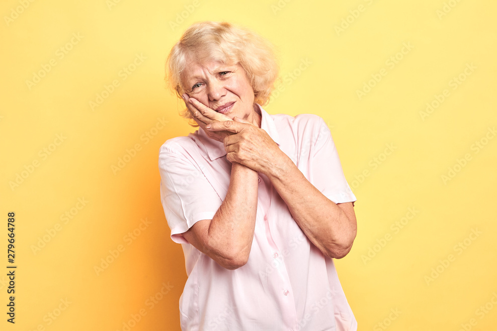 blonde woman touching cheek with hand as she has problems with teeth. dental illness Dentist concept.isolated yellow background. studio shot. blonde woman touching cheek with hand as she has problems with teeth. dental illness Dentist concept.isolated yellow background. studio shot.