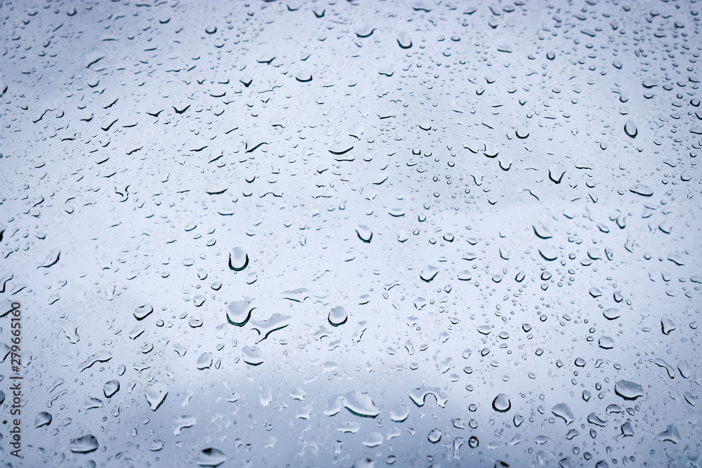 Large drops of water on the glass. Raindrops on the windshield of a car against the background of the sky sky.
