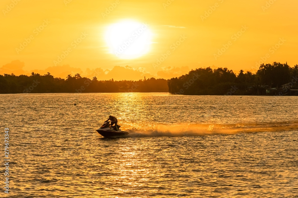 SURAT THANI, THAILAND, JULY 14, 2019: Silhouette man drive on the jet ski above the water at sunset in Surat Thani, Thailand..