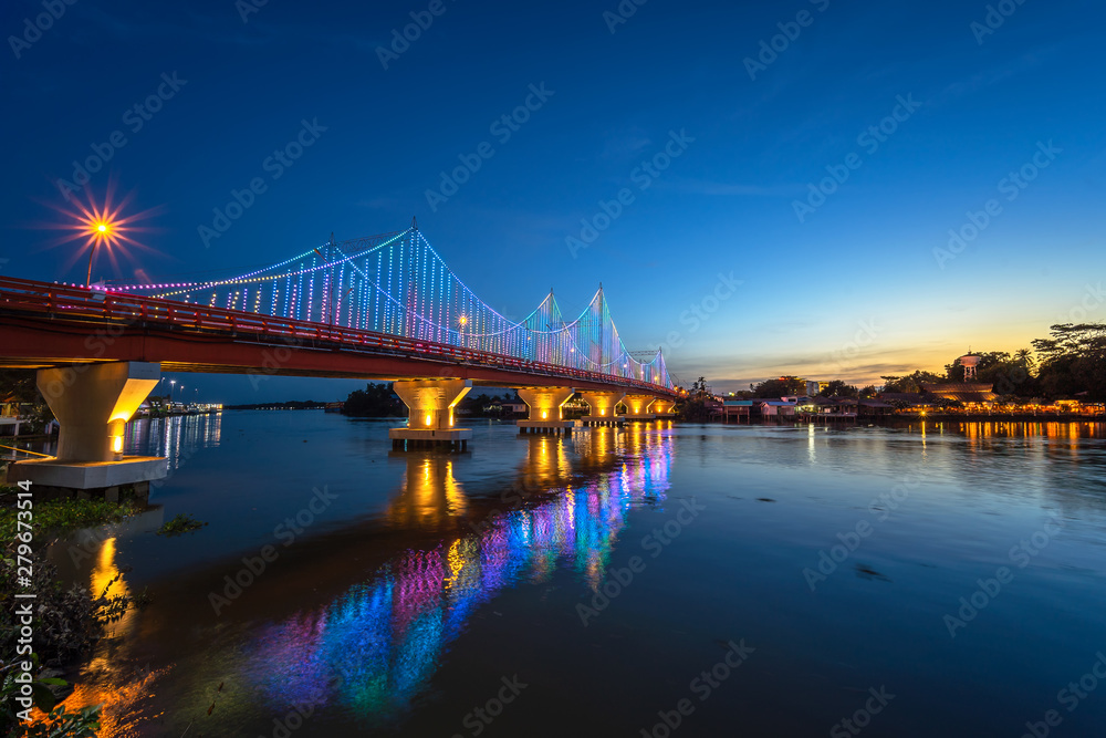 Fototapeta premium The city lights of Surat Thani at twilight with the Bridge and reflection over the Tapee River in Surat Thani , Thailand