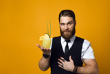 bearded barman with beard holding cocktail in waistcoat