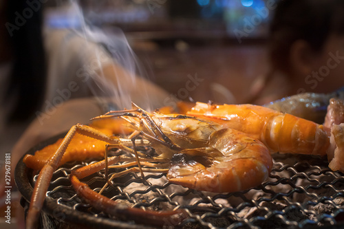 Hot Grill shrimps on the grilling basket and charcoal stove with smoke at the restaurant