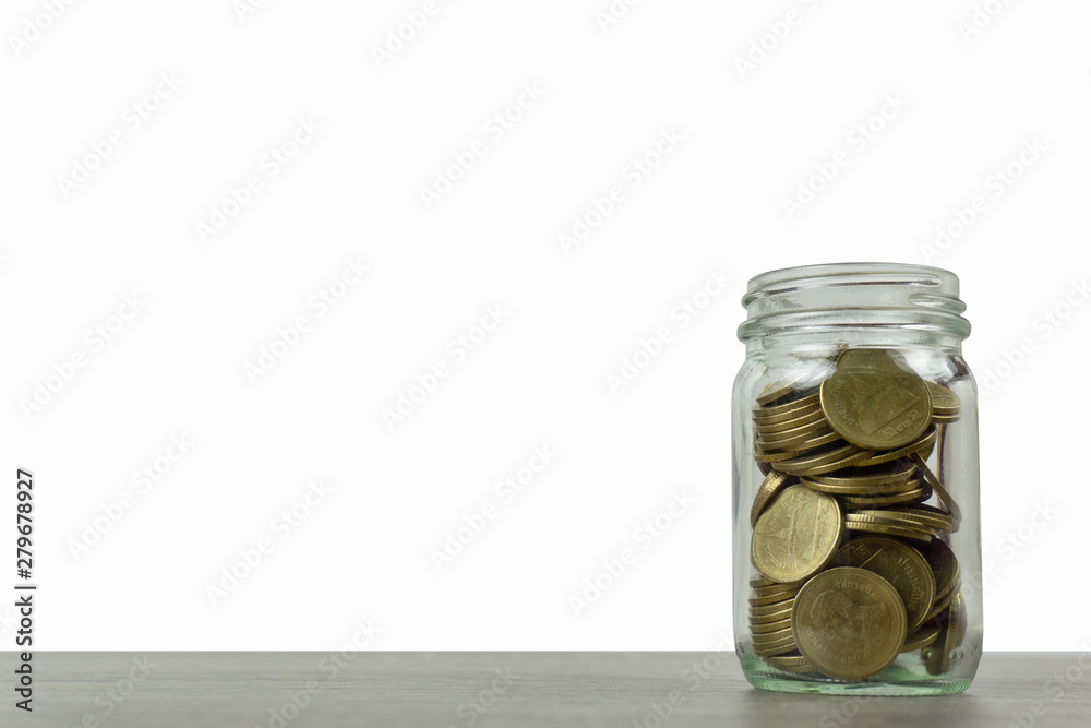 Savings and investment concepts. Stack of coins in a glass jar on wooden table isolated on white background and space.