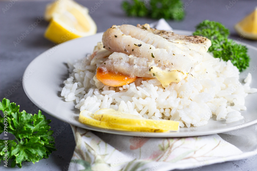 Fish baked with carrot, onion, parsley and sliced lemon on a grey plate with rice. Healthy dinner. Fish baked with carrot, onion, parsley and sliced lemon on a grey plate with rice. Healthy dinner.