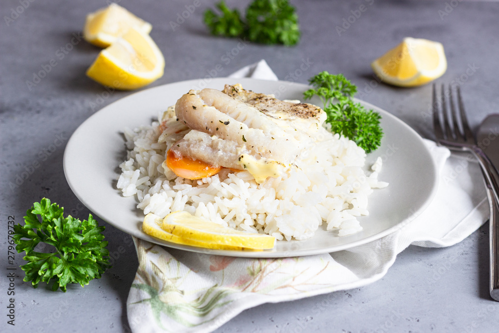 Fish baked with carrot, onion, parsley and sliced lemon on a grey plate with rice. Healthy dinner. Fish baked with carrot, onion, parsley and sliced lemon on a grey plate with rice. Healthy dinner.