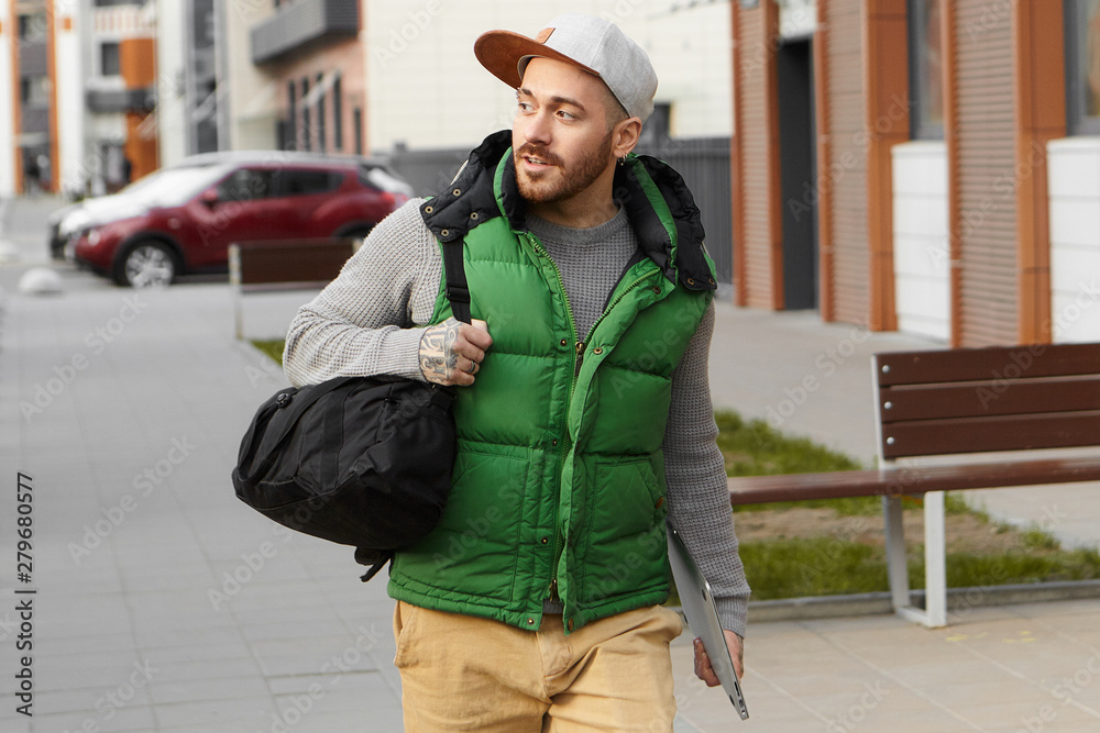 Urban lifestyle, technology and travel concept. Attractive fashionable young European man with stubble wearing stylish clothes, carrying black shoulder bag and digital tablet, going on business trip Urban lifestyle, technology and travel concept. Attractive fashionable young European man with stubble wearing stylish clothes, carrying black shoulder bag and digital tablet, going on business trip