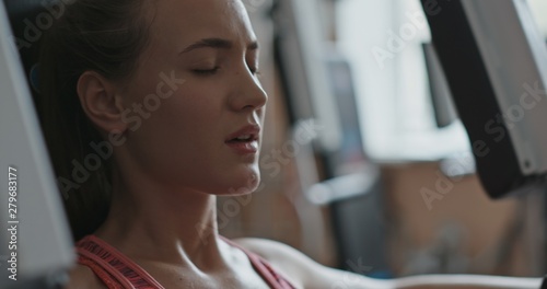 Young woman doing exercise in chest press machine