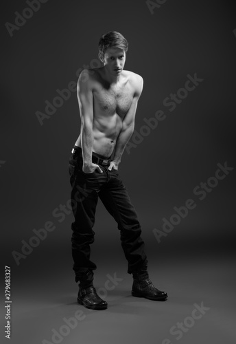 Full length portrait of a sexy young man in jeans and shirtless posing at studio.