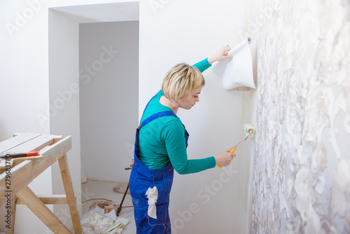 woman doing repairs in apartment wallpapering on wall