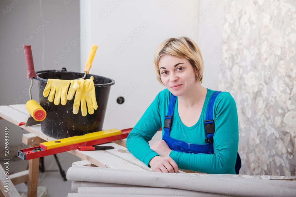 woman doing repairs in apartment wallpapering on wall woman doing repairs in apartment wallpapering on wall