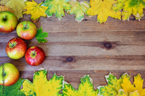 Apple and autumn maple leaves frame over wooden background
