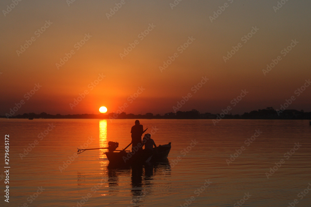 Atardecer en el rio, el barco muestra su silueta al contraste con el sol horizontal
