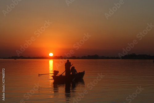 Atardecer en el rio, el barco muestra su silueta al contraste con el sol horizontal
