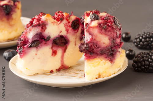 Delicious cottage cheese casserole with berries, cottage cheese pudding with berries. Appetizing cottage cheese casserole with blueberries, raspberries and blackberries on a dark gray background.