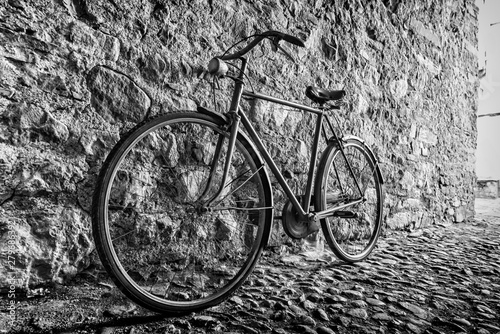 Old Bicycle in an alley next to a stone wall