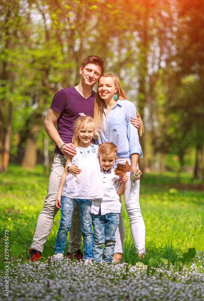 Portrait of family having fun in flowering city park on bright sunny day happily spending their leisure time together outdoors Portrait of family having fun in flowering city park on bright sunny day happily spending their leisure time together outdoors