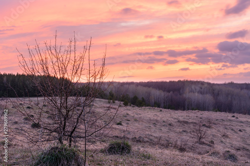 Beautiful spring landscape  sunset  trees  forest  mountains  hills  fields  meadows and sky. Gorgeous  red sky with heavy clouds at sunset. The spring.