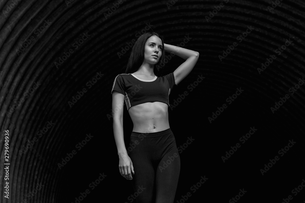 Sports woman posing in fashion sportswear on tunnel urban background. Fitness model working out outdoor. Black and white. Sports woman posing in fashion sportswear on tunnel urban background. Fitness model working out outdoor. Black and white.