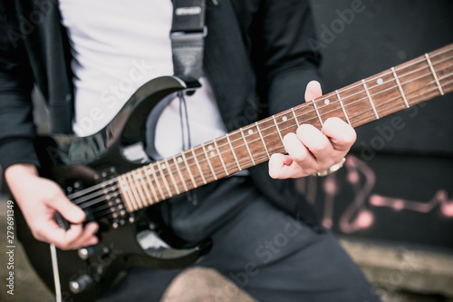 Man with a black electric guitar outdoors - blues rock music