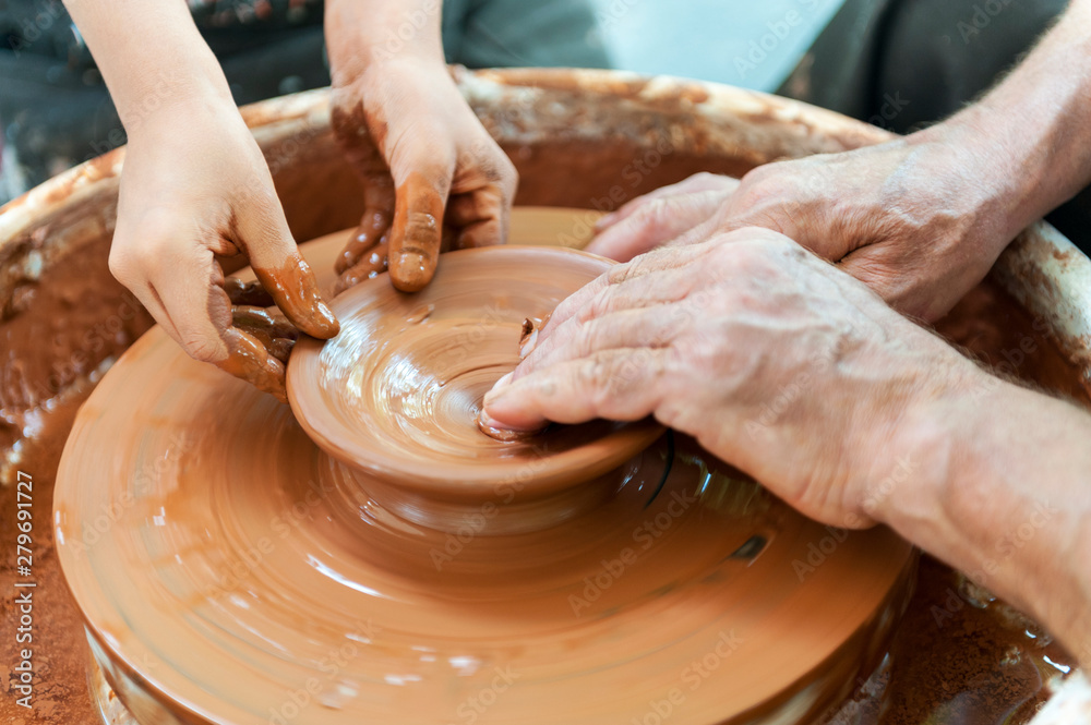 Handcrafted, Hands make clay. Master teaches the student to make pitcher on pottery wheel.
