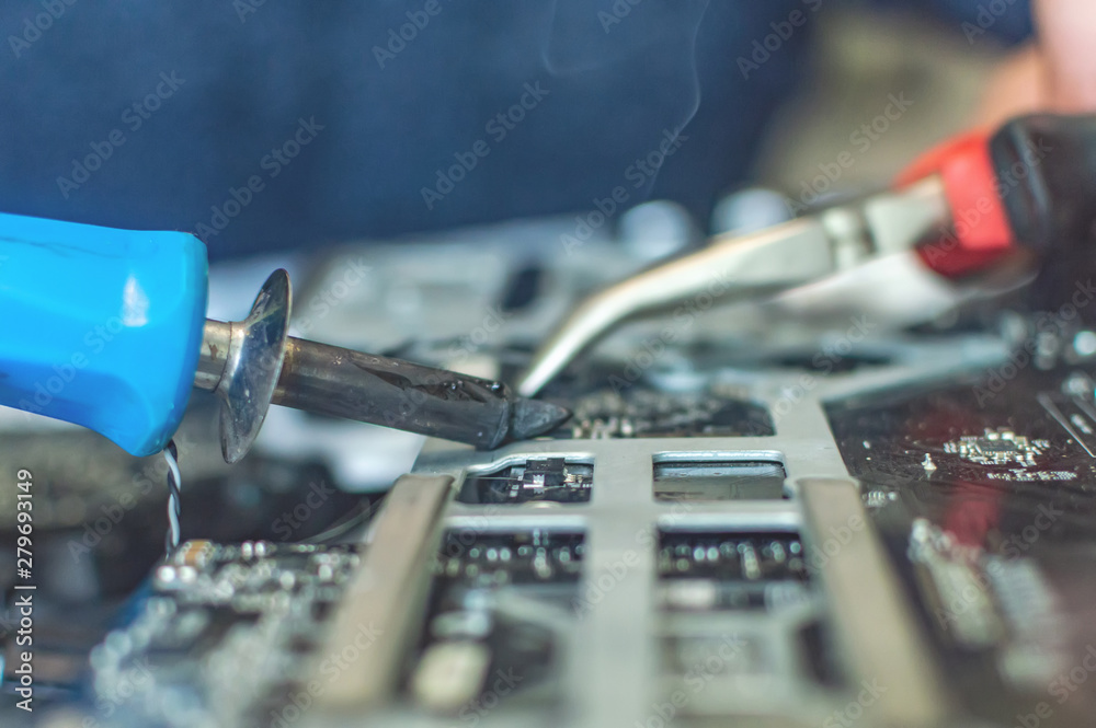 Fototapeta premium a man repairs a computer, solders a board, repairs electronics and modern technologies