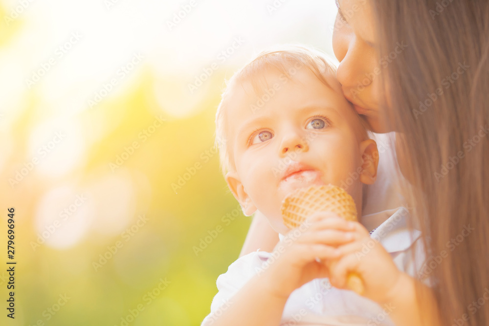 Mom kisses child son, boy eats ice cream in park Mom kisses child son, boy eats ice cream in park