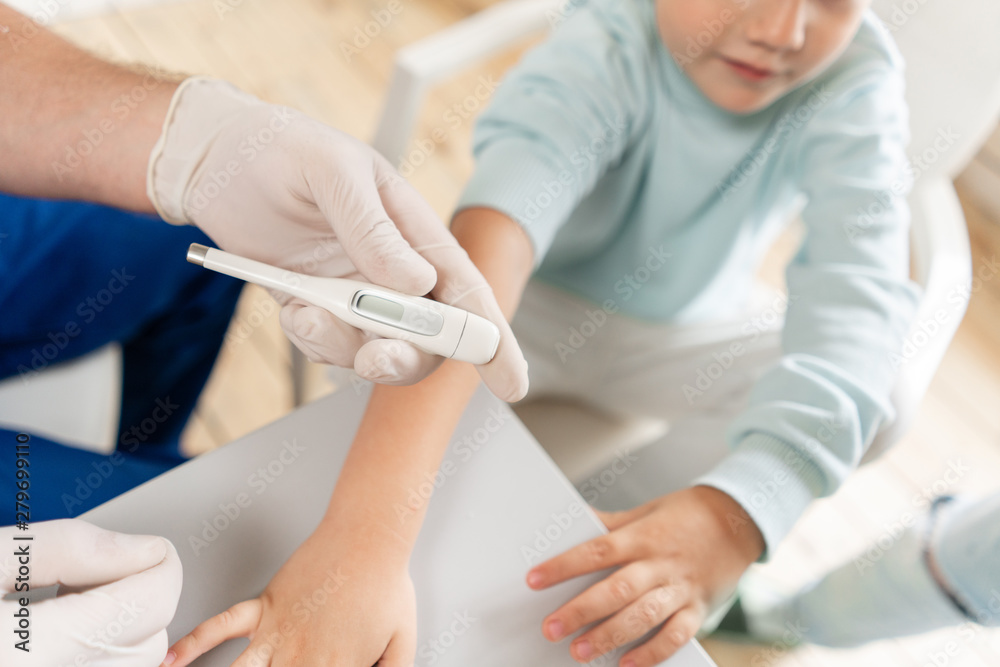 Male arm hold electronic thermometer showing high temperature. Pediatrician in the hospital Male arm hold electronic thermometer showing high temperature. Pediatrician in the hospital