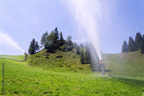 Snow making machines used to water grass on slope, sunny summer day, Wagrain ski resort, Austria