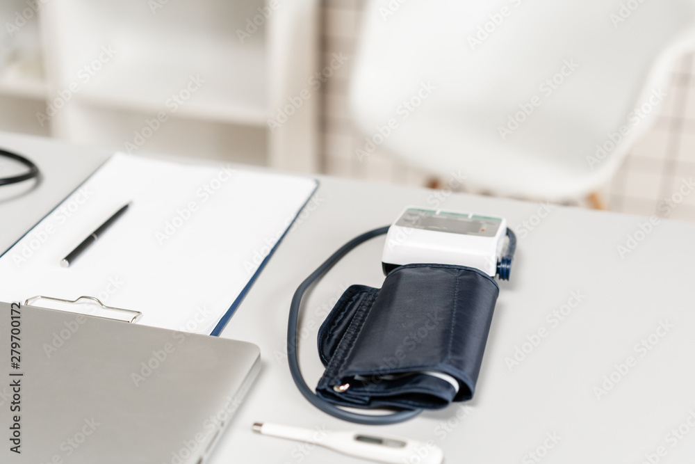 Workplace of doctor with laptop, stethoscope and notebook on wooden table in the office. Blood Pressure Monitor. Medical equipment. Cardiac diagnosis. vintage tone. Workplace of doctor with laptop, stethoscope and notebook on wooden table in the office. Blood Pressure Monitor. Medical equipment. Cardiac diagnosis. vintage tone.