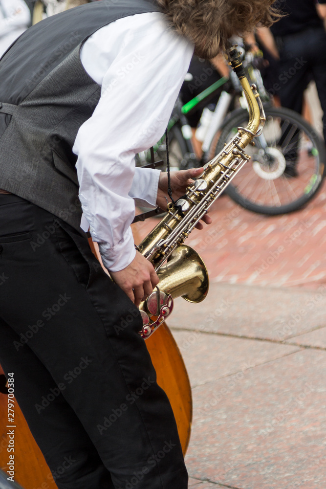 Naklejka premium Street musician's hands playing saxophone in an urban environment.