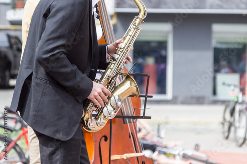 Street musician s hands playing saxophone and double-bass in an urban environment.