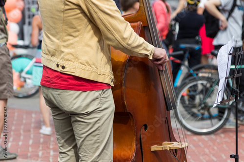 Street musician's hands playing double-bass in an urban environment.