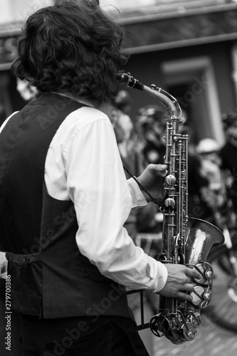 Street musician's hands playing saxophone in an urban environment. Black and white picture