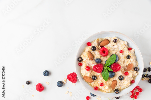 healthy homemade oatmeal porridge with berries, nuts and mint. diet breakfast food concept. top view