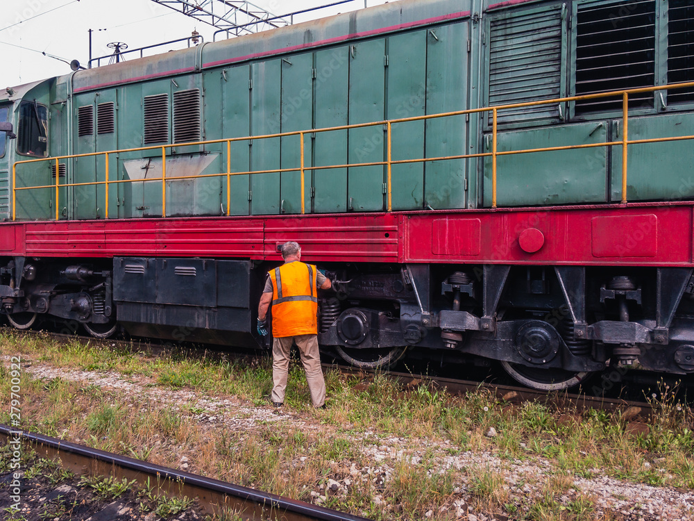 The Machinist of a diesel locomotive conducts locomotive maintenance on a sunny summer day. The Machinist of a diesel locomotive conducts locomotive maintenance on a sunny summer day.
