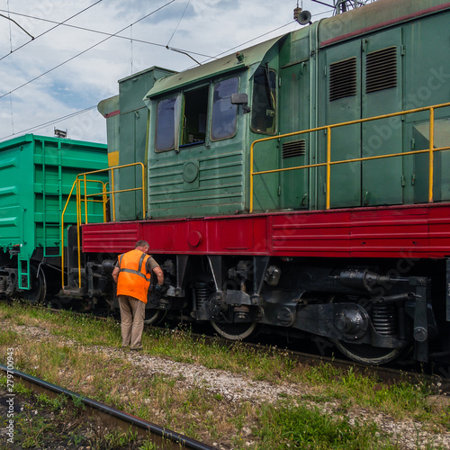 Locomotive driver performs locomotive maintenance on a sunny summer day.