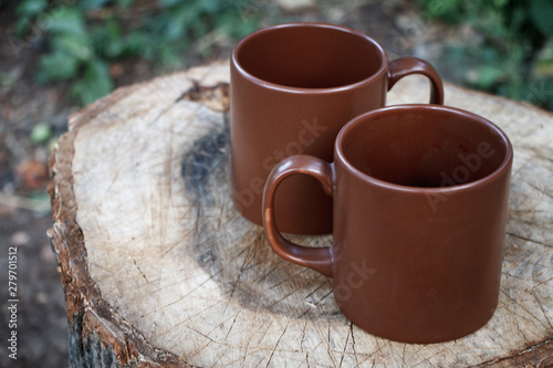 Close-up of two brown clay empty cups on a wooden stump