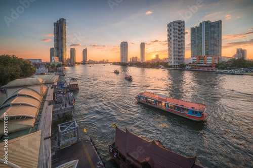 Chao Phraya River with Skyscrapers and Sathon Pier with Boats at Sunset as Seen from Taksin Bridge in Bangkok, Thailand photo