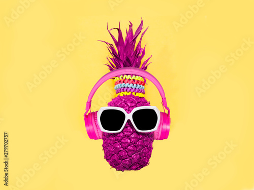 Pineapple in pink headphones and glasses on a yellow background
