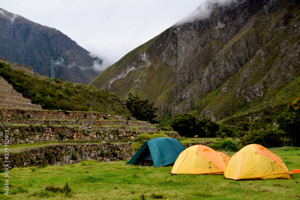 Camping in the mountains on a cloudy day with tents next to old ruins on the Inca trail to Machu Picchu in Peru
