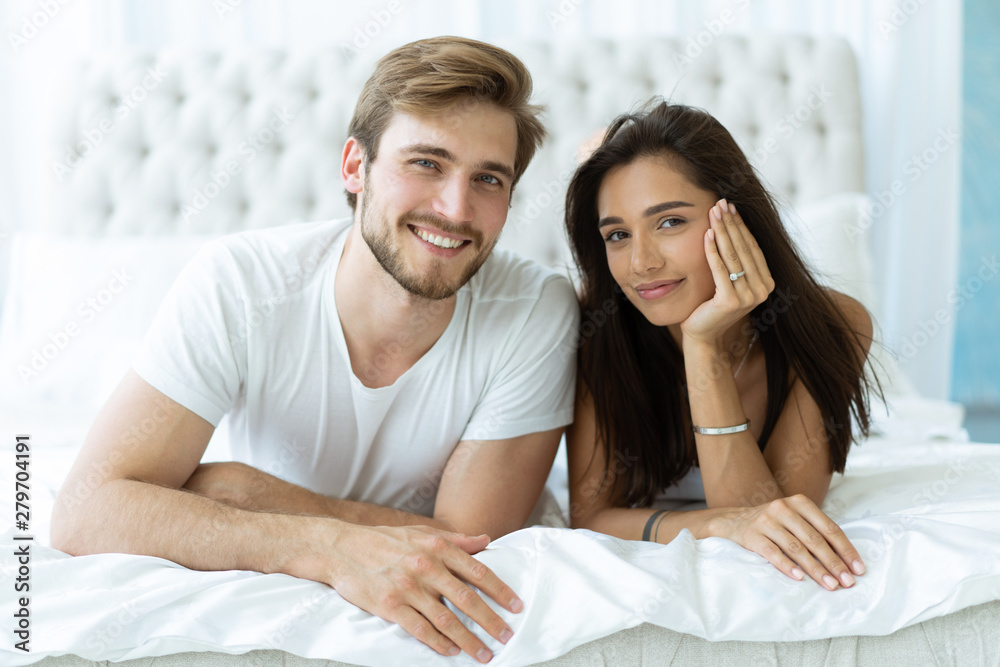 Young happy couple lying together in bed. Young happy couple lying together in bed.