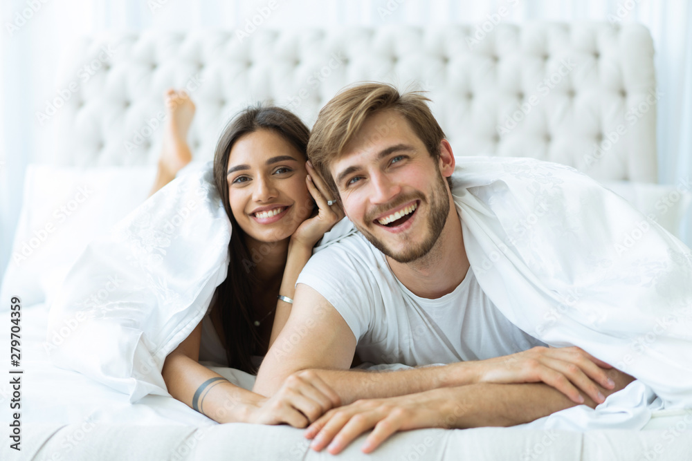 Young happy couple lying together in bed. Young happy couple lying together in bed.