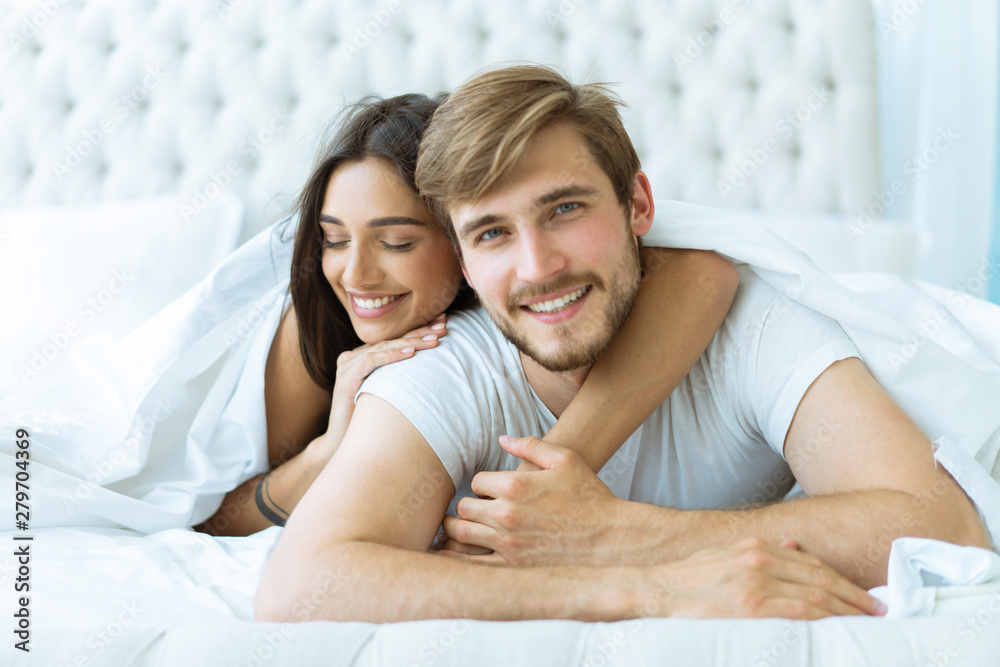 Young happy couple lying together in bed. Young happy couple lying together in bed.