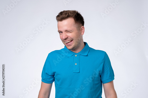 Happy sly man in blue t-shirt winking an eye