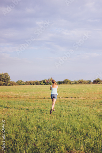 Running girl in the field with a bouquet