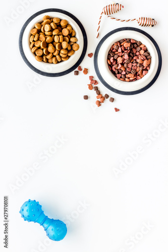 Dry pet food in bowls and cat toys on white background top view space for text